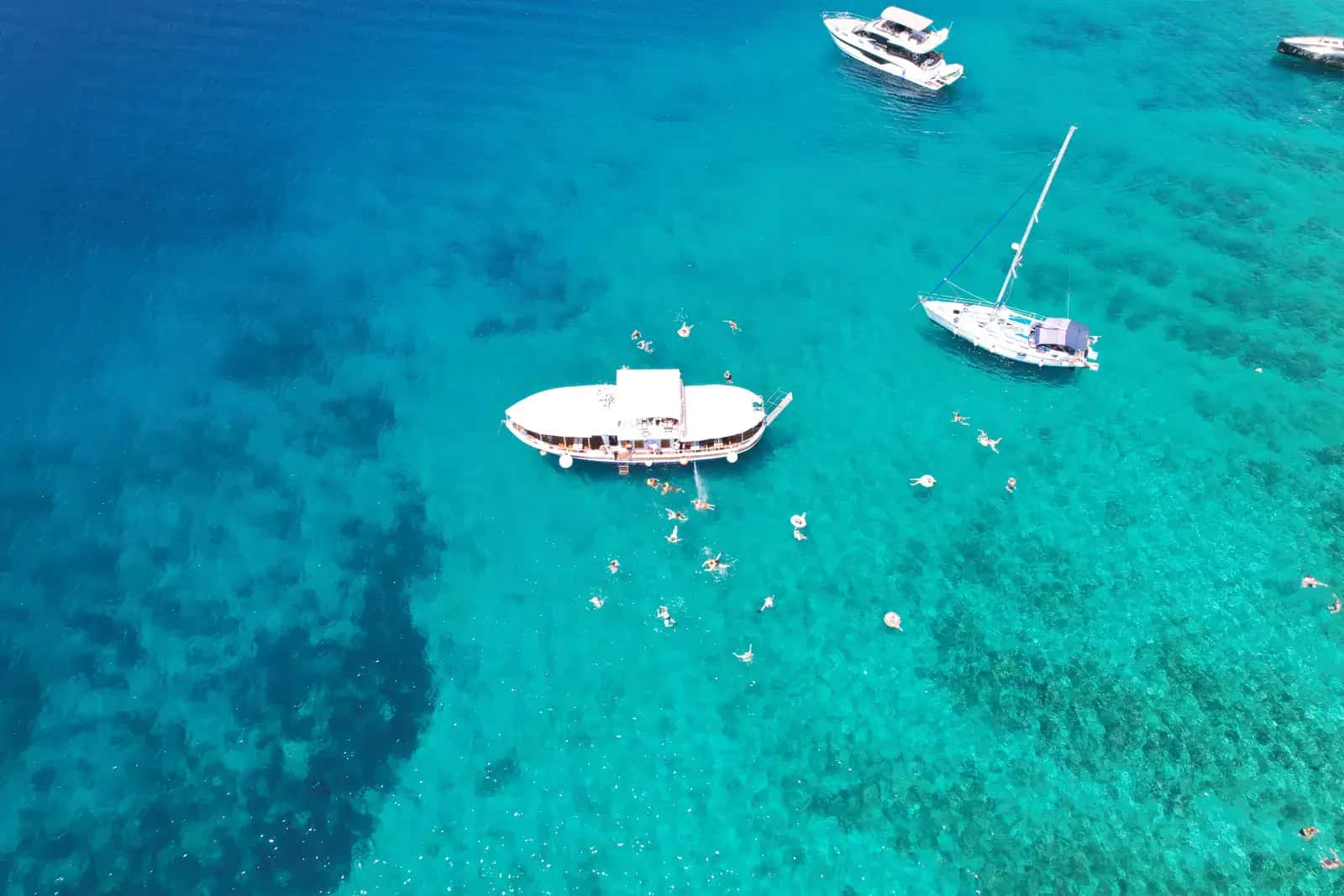 Aerial view of our traditional wooden tour boat anchored at the Blue Lagoon in Croatia, with swimmers in the turquoise water around the boat